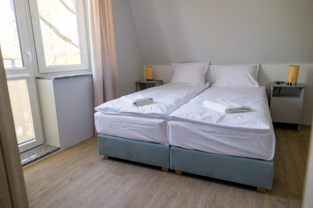 Przestronny apartament dla 4 osób w obiekcie Leśna Chwila. Jasne wnętrze z wygodnymi łóżkami, przygotowane na wypoczynek w cichej części Polanicy.